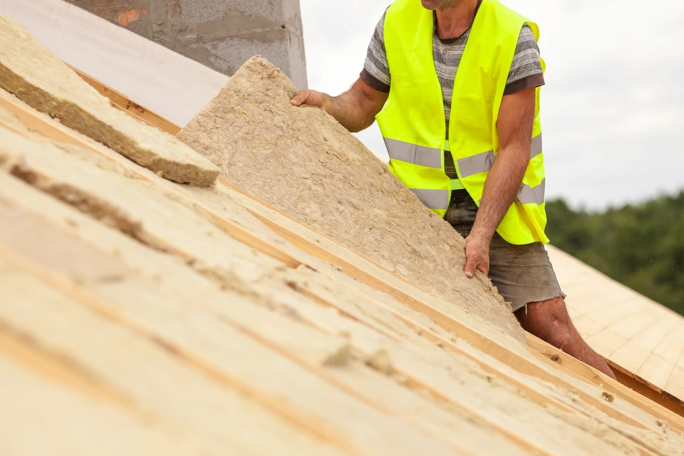 Ouvrier du b&acirc;timent du toit installant du mat&eacute;riau d'isolation du toit sur une nouvelle maison en construction
