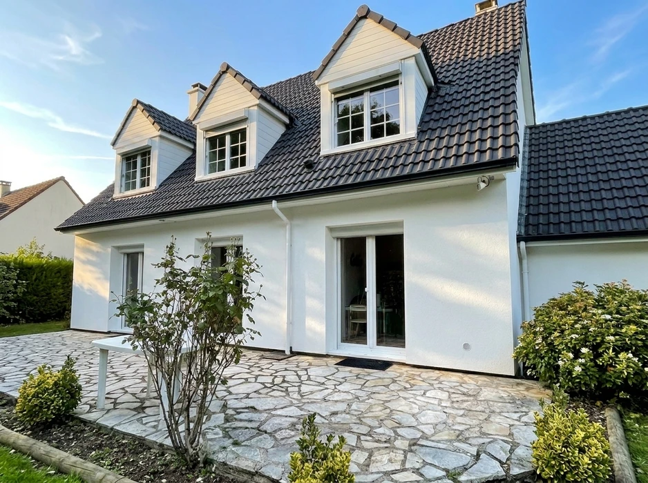 Maison individuelle de style normand, façade blanche avec toit en tuiles ardoisées anthracite, lucarnes à fenêtres à petits-bois