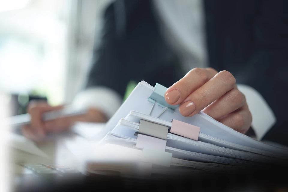 Conseiller professionnel en tenue business présentant un devis ou un dossier d'aide financière à un couple de propriétaires dans le salon de leur maison, avec l'arrière-plan montrant les murs ou structures de la maison. L'interaction doit être naturelle et confiante, reflétant une relation de conseil transparent et rassurant, sans cliché ou mise en scène exagérée.