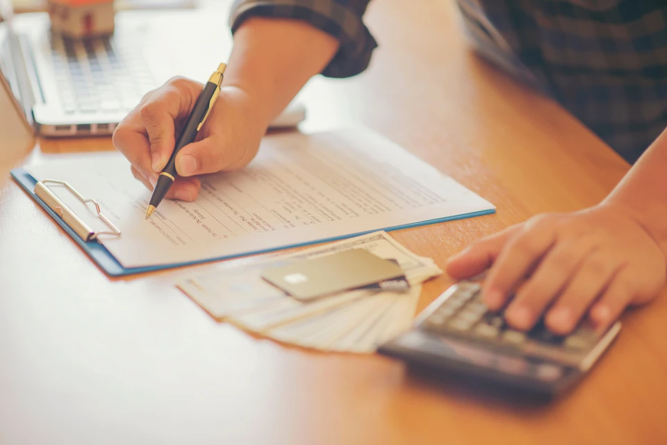 Une femme en intérieur remplit un formulaire de type checklist, cochant des cases avec un stylo