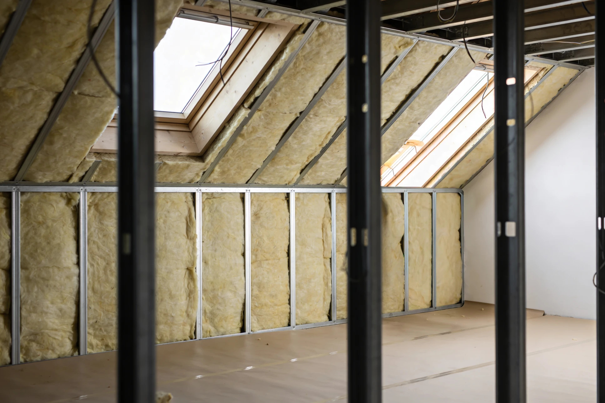 Ouvrier en équipement de protection individuelle installant l'isolation thermique dans une construction résidentielle