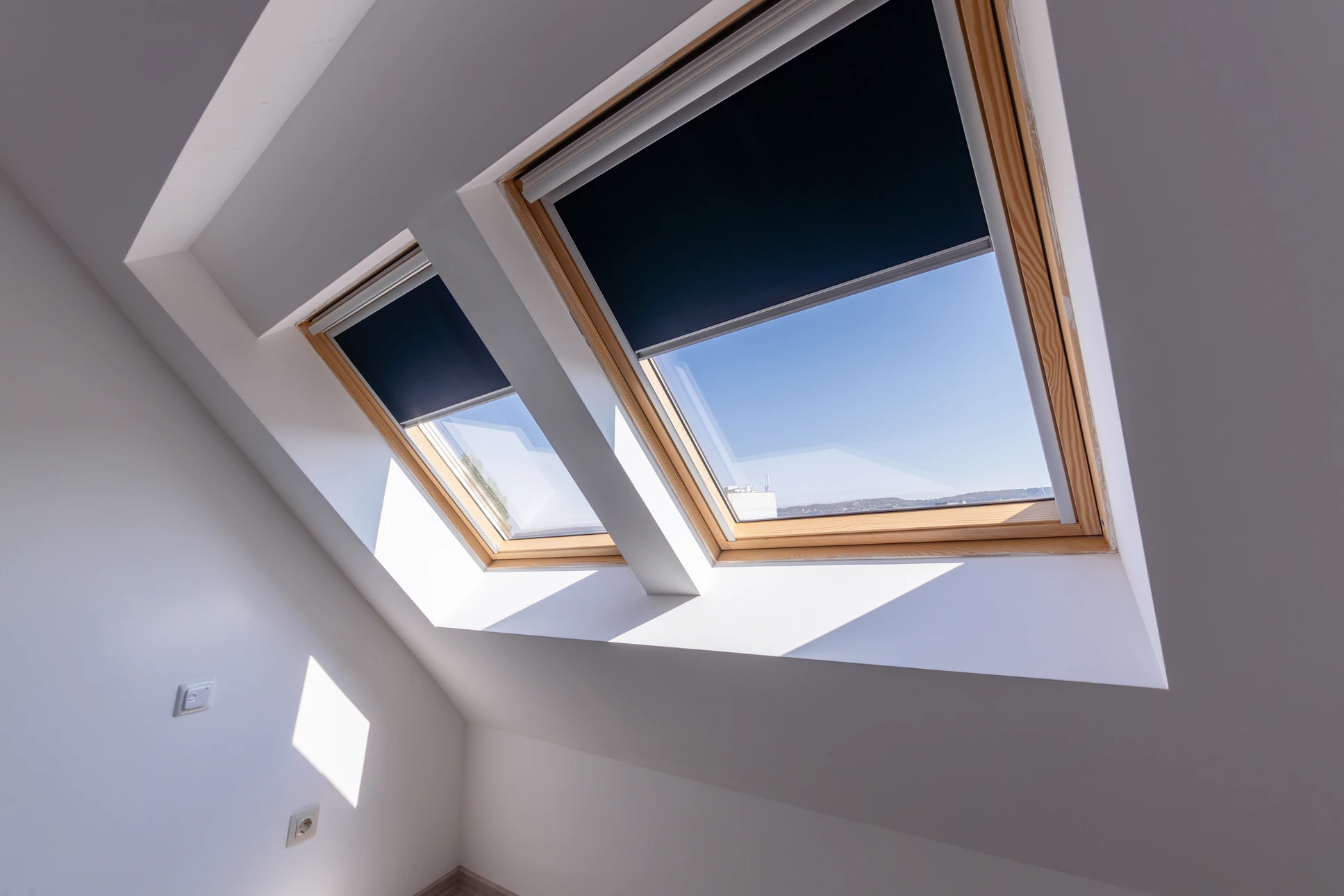 Photographie d'un espace sous combles lumineux et accueillant, avec une ou deux fenêtres de toit Velux installées dans la toiture, laissant entrer généreusement la lumière naturelle. La pièce est décorée de manière professionnelle et moderne, avec mobilier contemporain discret pour mettre l'accent sur la clarté apportée par la fenêtre. La lumière du jour illumine clairement l'espace, soulignant le contraste entre l'espace avant et après installation du Velux.